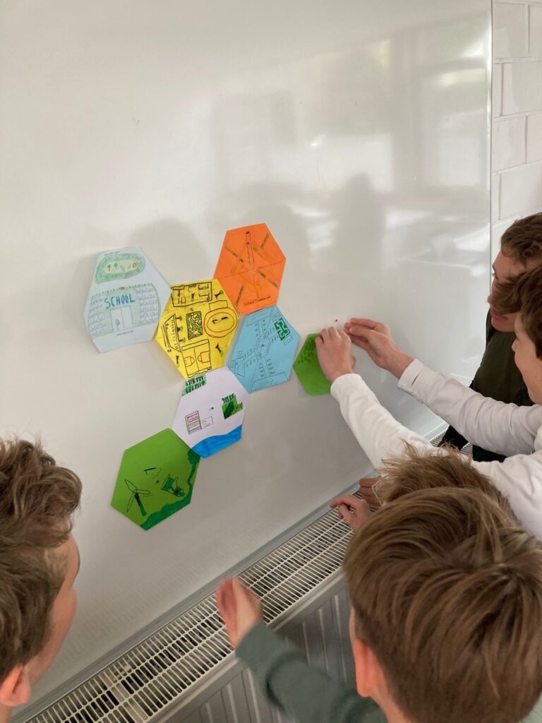 Leerlingen bij een whiteboard waar ze met post-its hun plan voor de Stad van de Toekomst uitwerken